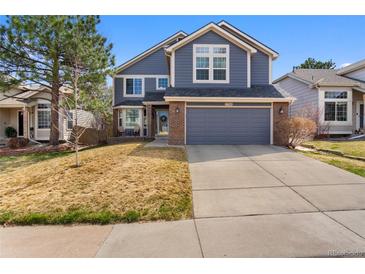 Charming two-story home featuring blue siding, brick accents, an attached two-car garage, and a well-maintained front yard at 17018 Carr Ave, Parker, CO 80134