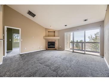 Open living room featuring a fireplace and sliding glass doors leading to a balcony at 7415 S Alkire St # 302, Littleton, CO 80127