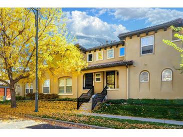 Charming townhouse exterior featuring a well-maintained lawn and autumnal tree at 7704 E 25Th Ave, Denver, CO 80238