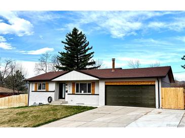 Charming single-story home with a well-manicured lawn, mature trees, and a two-car garage at 1853 S Urban Way, Lakewood, CO 80228