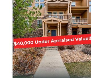 Inviting townhouse featuring a stone facade, covered balconies, and well-maintained landscaping at 5574 W 72Nd Dr, Arvada, CO 80003