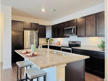 Modern kitchen boasts granite counters, dark wood cabinets, stainless appliances, and a functional kitchen island with barstool seating at 9283 Twenty Mile Rd # 308, Parker, CO 80134