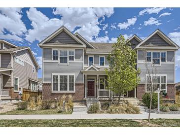 Charming two-story home with gray siding, brick accents, and well-maintained landscaping under a partly cloudy sky at 14176 Jackson St, Thornton, CO 80602