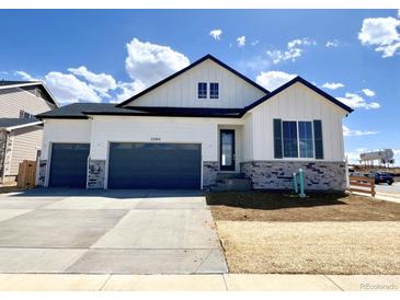 Charming two-story home with a three car garage, stone accents, and black trim against white siding at 25204 E Warren Pl, Aurora, CO 80018
