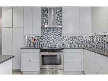 Modern kitchen features white cabinets, stainless steel appliances, and gray diamond patterned backsplash at 482 W Caley Ave, Littleton, CO 80120