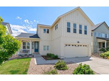 Charming two-story home with a blue front door, attached two car garage, and a well-manicured lawn at 4670 Tanner Peak Trl, Brighton, CO 80601