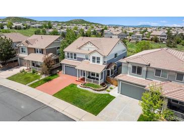 Inviting two-story home with manicured lawn and a cozy front porch, complete with a two-car garage and a red driveway at 2307 Candleglow St, Castle Rock, CO 80109