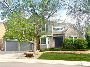 Charming two-story home with brick and gray siding, mature trees, manicured lawn, and an attached two-car garage at 2990 E 135Th Dr, Thornton, CO 80241