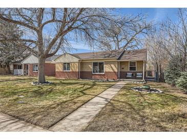 Charming single story brick home with a manicured lawn, mature trees, and inviting walkway at 1261 S Harrison St, Denver, CO 80210