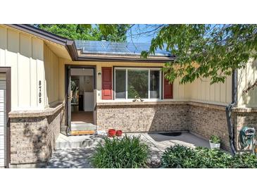 Charming home entrance with solar panels, brick accents, and an open doorway, inviting guests inside at 8705 W 86Th Dr, Arvada, CO 80005