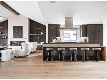 A modern kitchen features a central island with bar seating, a sleek range hood, and hardwood floors at 3112 Braun Ct, Golden, CO 80401
