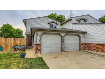 Charming townhouse with two-car garage, red brick accents and lush green lawn at 12556 Elm St, Thornton, CO 80241