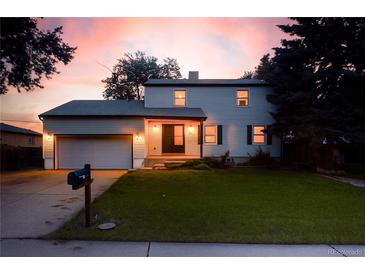Charming two-story home with a well-maintained lawn and an attached garage, showcased at sunset at 7431 Webster St, Arvada, CO 80003
