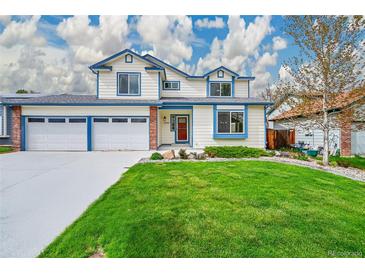 Charming two-story home with a lush green lawn, blue trim, and a three-car garage at 12287 W Aqueduct Dr, Littleton, CO 80127