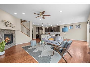 Bright, open living room features a cozy fireplace and a ceiling fan, seamlessly connected to the kitchen at 844 Dakota Ln, Erie, CO 80516