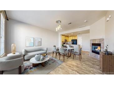 Open-concept living room features a fireplace, dining area and adjacent kitchen space, creating a warm, inviting atmosphere at 16047 E Geddes Ln # 128, Aurora, CO 80016