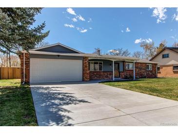 Charming single-story home features brick accents, attached garage, and well-maintained front lawn at 9880 W 76Th Pl, Arvada, CO 80005