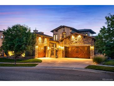 Beautiful home featuring a stone facade, multiple car garage, and manicured front lawn at dusk at 2117 S Juniper St, Lakewood, CO 80228