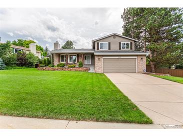 Charming two-story home featuring a brick facade, manicured lawn, and a two-car attached garage at 8588 S Woody Way, Highlands Ranch, CO 80126