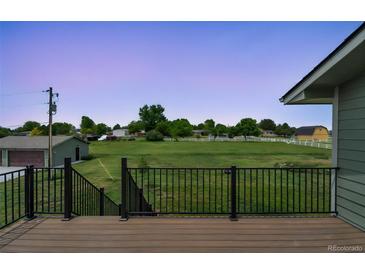Relaxing back deck area overlooking a grassy field with white fence and barn at 15545 Lipan St, Broomfield, CO 80023