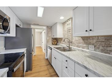 Modern kitchen featuring white cabinets, stainless steel appliances, and attractive stone backsplash at 9700 E Iliff Ave # 81, Denver, CO 80231