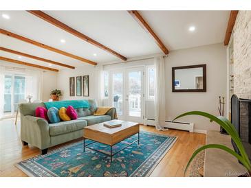 Bright living room with wood beams, hardwood floors, and a cozy fireplace at 11845 W 30Th Pl, Lakewood, CO 80215