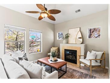 Cozy living room featuring a fireplace, ceiling fan, plush seating, and multiple bright windows at 9804 Martin Luther King Blvd, Denver, CO 80238