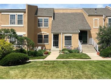 Charming townhome featuring manicured lawn, mature trees, and colorful flowerbeds enhancing the curb appeal at 13187 E Bethany Pl, Aurora, CO 80014