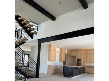 Modern kitchen with island, light wood cabinets, stainless appliances, and unique floating stairs with black metal railings at 2442 S Saint Paul St, Denver, CO 80210