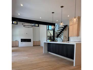 Open living room with hardwood floors, modern lighting, and staircase at 2442 S Saint Paul St, Denver, CO 80210