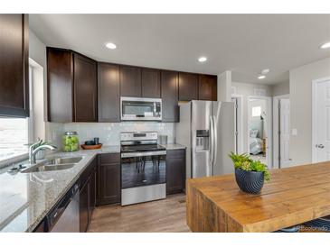 Modern kitchen features stainless steel appliances, granite countertops, and wooden cabinets at 46550 Avery Ln, Bennett, CO 80102