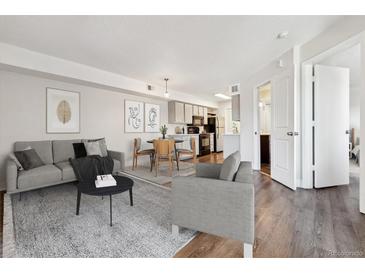 Bright living room with modern decor, stylish furnishings, and hardwood floors leading to dining area and kitchen at 1820 Newland Ct # 210, Lakewood, CO 80214