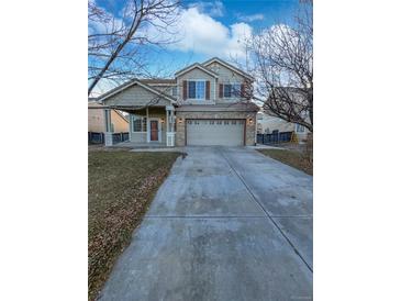 Inviting two-story home with a spacious driveway and manicured lawn under a partly cloudy sky at 19512 E 58Th Dr, Aurora, CO 80019