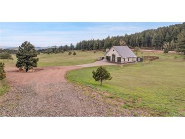 Beautiful home surrounded by lush green grounds and towering trees at 5166 Bear Mountain Dr, Evergreen, CO 80439