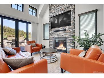 Inviting living room featuring a stone fireplace, comfortable seating, and large windows at 5166 Bear Mountain Dr, Evergreen, CO 80439