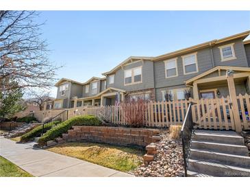Charming townhome features gray siding, a picket fence, and a well-maintained front yard at 17922 E 104Th Pl # D, Commerce City, CO 80022
