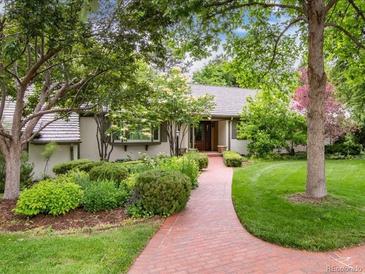 Charming single-story home featuring a lush front yard, brick pathway, and meticulously landscaped garden beds at 3975 S Cherry St, Cherry Hills Village, CO 80113