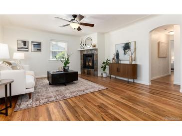 Bright living room features hardwood floors, a ceiling fan, and a stone fireplace at 4197 S Grant St, Englewood, CO 80113