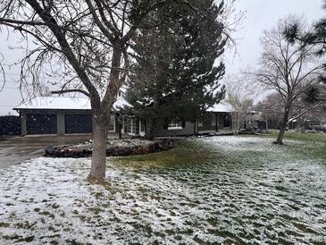Charming single-story home featuring a well-manicured lawn and a three car garage, partially covered in snow at 8659 E Kenyon Ave, Denver, CO 80237
