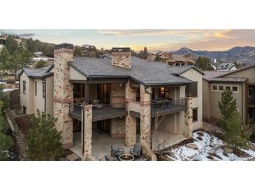 Stunning rear exterior view of a multi-level home, featuring stone accents and expansive deck overlooking scenic mountain landscape at 8246 Raphael Ln, Littleton, CO 80125