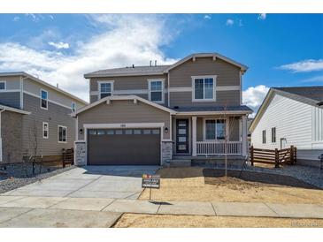 Two-story home featuring a two-car garage and covered porch, set against a bright blue sky with scattered clouds at 1312 Sienna Peak Cir, Erie, CO 80516