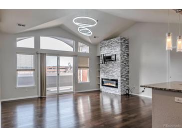 Bright living room with modern fireplace, mounted TV, hardwood floors, and balcony access at 14251 E 1St Dr # 308, Aurora, CO 80011