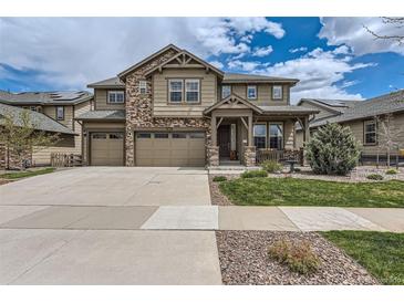 Charming two-story home with a stone and siding exterior, well-manicured lawn, and a three car garage at 8133 Arapahoe Peak St, Littleton, CO 80125