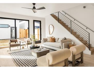 Bright living room features modern furniture, a ceiling fan, and stairs leading to the second floor at 2391 King St, Denver, CO 80211