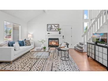 Bright living room features a fireplace, white sofa with patterned cushions, and wood floors at 1248 W 135Th Ave, Denver, CO 80234