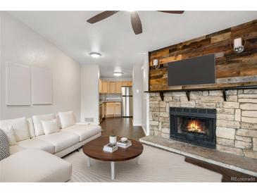 Inviting living room featuring a stone fireplace, sofa, and wood floors at 185 S Sable Blvd # T18, Aurora, CO 80012