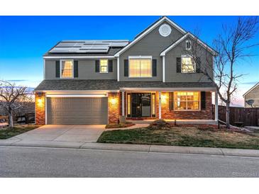 Inviting two-story home with a brick facade, solar panels and a well-manicured front yard at 9957 Candlewood Ln, Highlands Ranch, CO 80126
