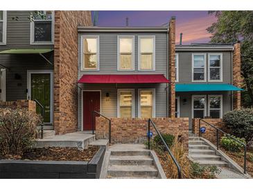 Gray townhome exterior with red and teal awnings, brick accents, and steps leading to the entrance at 1150 Inca St # 59, Denver, CO 80204