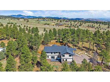 Beautiful aerial view of an elegant home surrounded by lush greenery and mountain views at 24701 Us Hwy 40, Golden, CO 80401