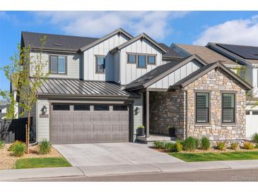 Charming two-story home features stone accents, gray siding, and a well-manicured lawn, creating inviting curb appeal at 11103 Cloud Shadow St, Littleton, CO 80125